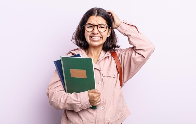 Bela jovem se sentindo estressada, ansiosa ou com medo, com as mãos na cabeça. estudante com conceito de livros