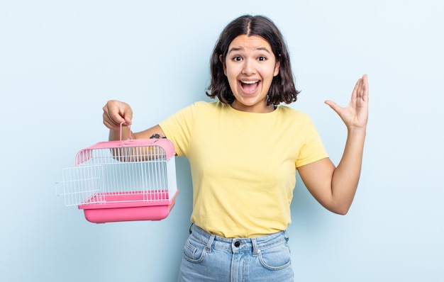 Bela jovem se sentindo feliz e surpresa com algo inacreditável. conceito de gaiola para animais de estimação