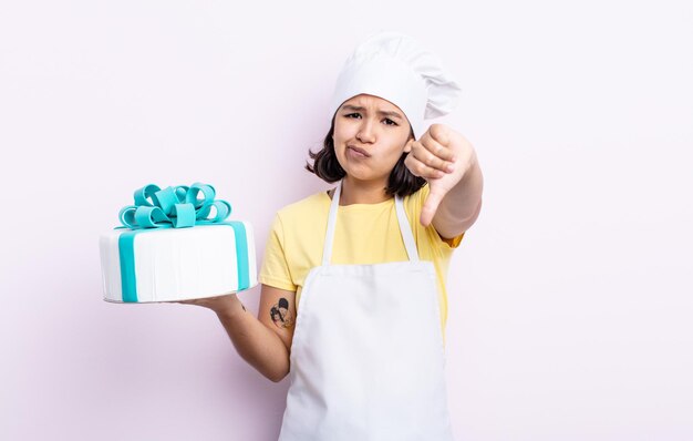 Bela jovem se sentindo mal, mostrando os polegares para baixo. chef cozinhando um bolo