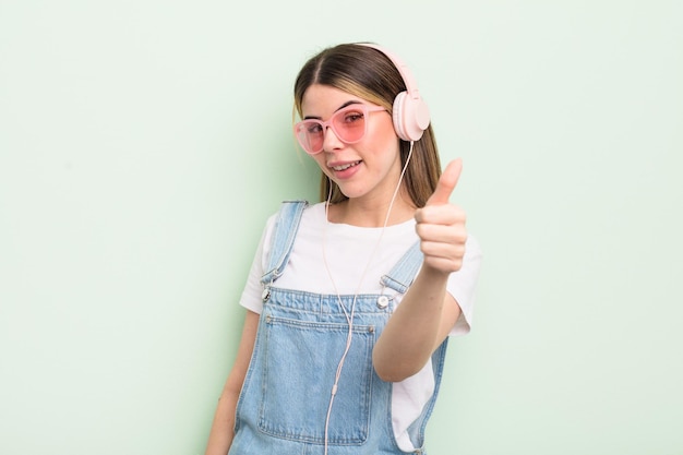 Bela jovem se sentindo orgulhosa sorrindo positivamente com polegares para cima ouvindo o conceito de música