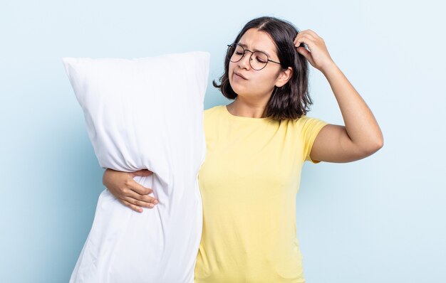 Bela jovem se sentindo perplexa e confusa, coçando a cabeça. conceito de cama