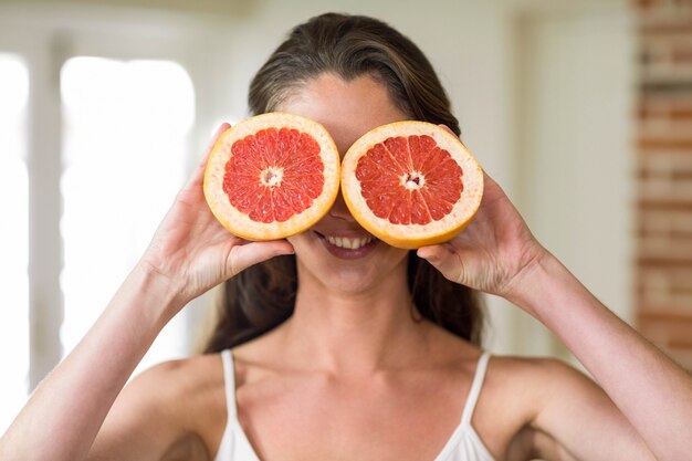 Bela jovem segurando fatias de laranja de sangue na cozinha