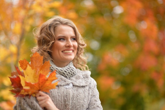 Bela jovem segurando folhas de outono no parque