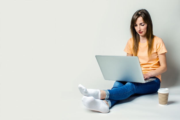 Bela jovem segurando um laptop e tomando café