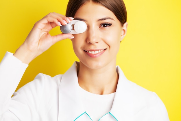 Bela jovem segurando um recipiente com lentes de contato para a visão