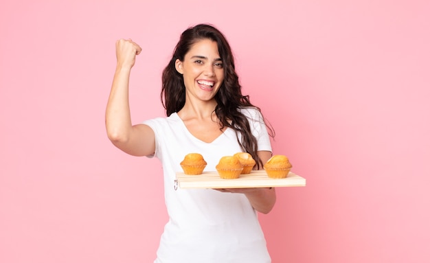 Bela jovem segurando uma bandeja de muffins