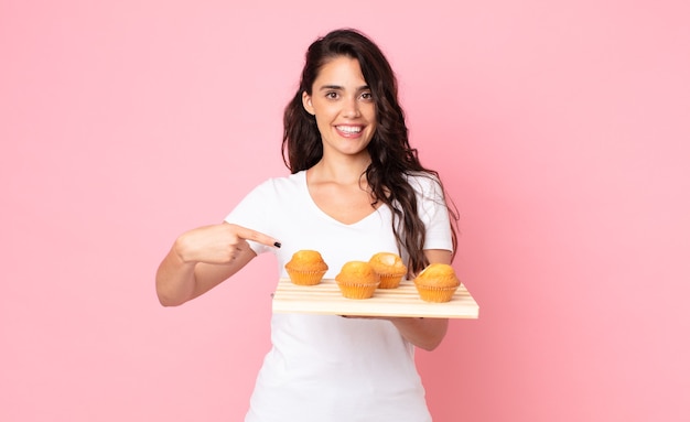 Bela jovem segurando uma bandeja de muffins