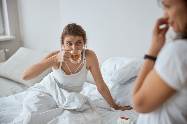 Bela jovem sentada na cama ouvindo o parceiro