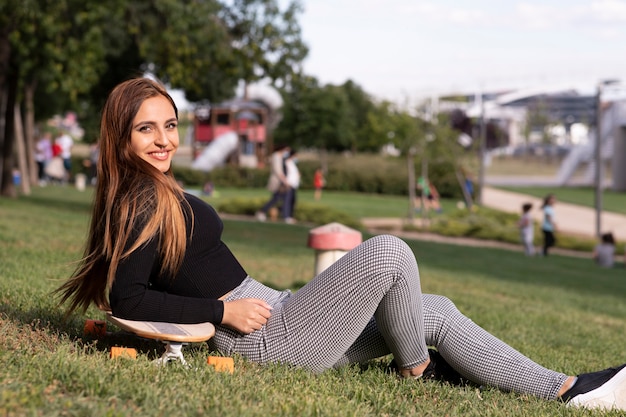 Bela jovem sentada no seu skate no parque