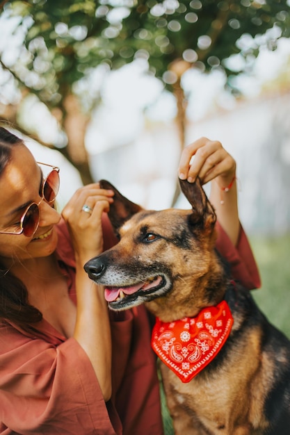 Foto bela jovem sorridente com óculos de sol joga e abraça seu cachorro no parque dono feliz e animal de estimação cachorro resgatado de um abrigo