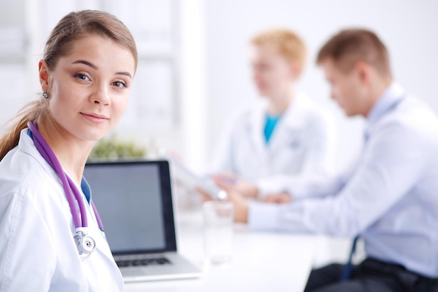 Bela jovem sorridente médica sentada à mesa.