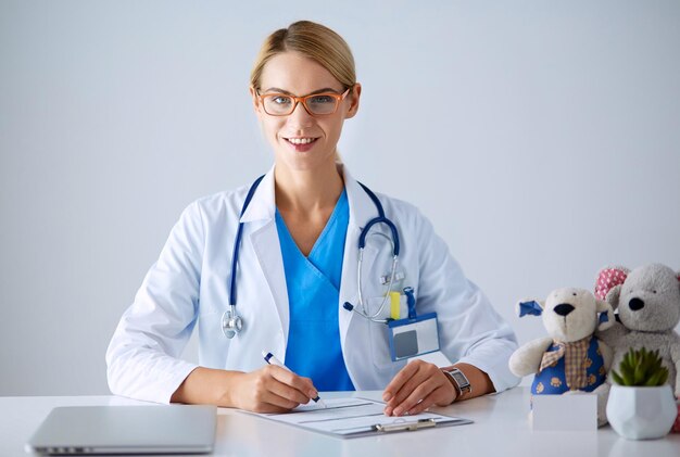 Bela jovem sorridente médica sentada à mesa.