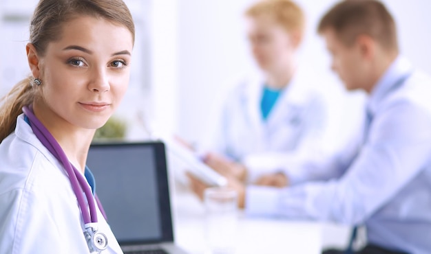 Bela jovem sorridente médica sentada à mesa.