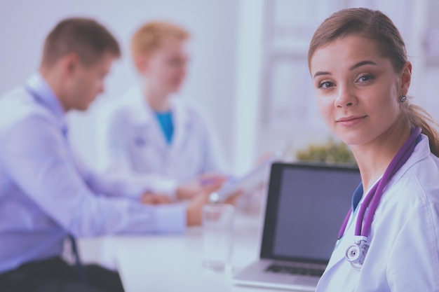 Bela jovem sorridente médica sentada à mesa.