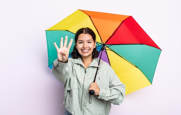 Bela jovem sorrindo e parecendo amigável, mostrando o número quatro. conceito de chuva e guarda-chuva