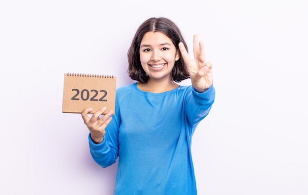 Bela jovem sorrindo e parecendo amigável, mostrando o número três. conceito de calendário 2022