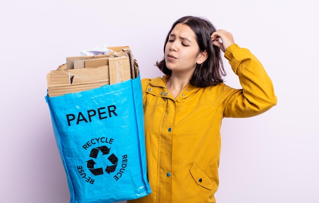 Bela jovem sorrindo feliz e sonhando acordada ou duvidando. conceito de reciclagem de papel