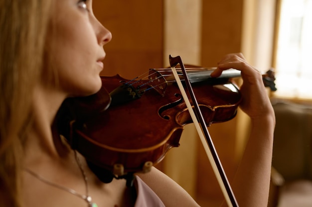 Bela jovem tocando violino. Desempenho de músico feminino romântico closeup