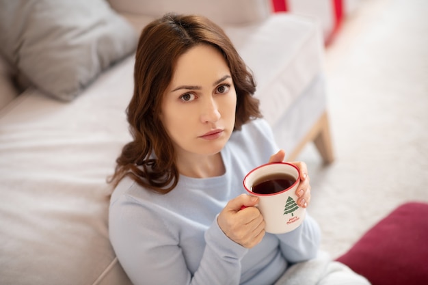 Bela jovem tomando café sentada no chão