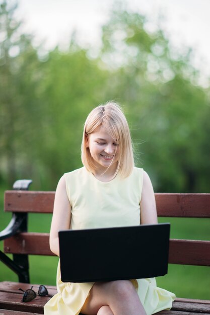 bela jovem trabalhando em um laptop no parque, garota freelancer na natureza