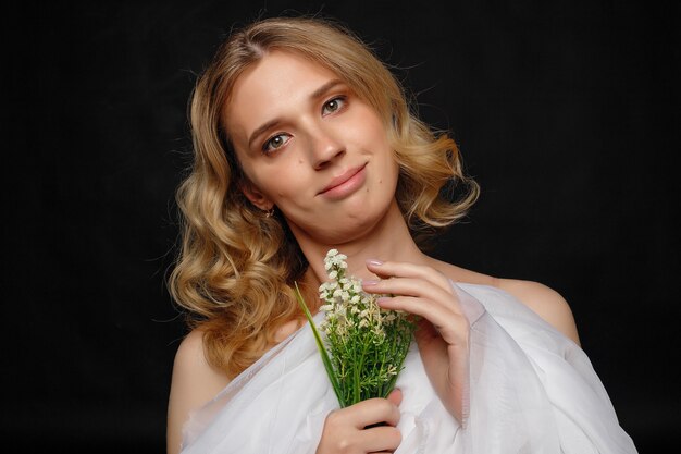 Bela jovem transexual com cabelo loiro segurando flores