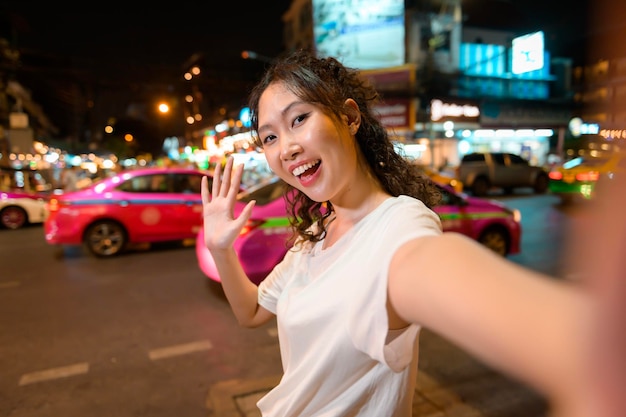 Bela jovem turista asiática em turismo de férias e explorando a estrada de Khao San à noite