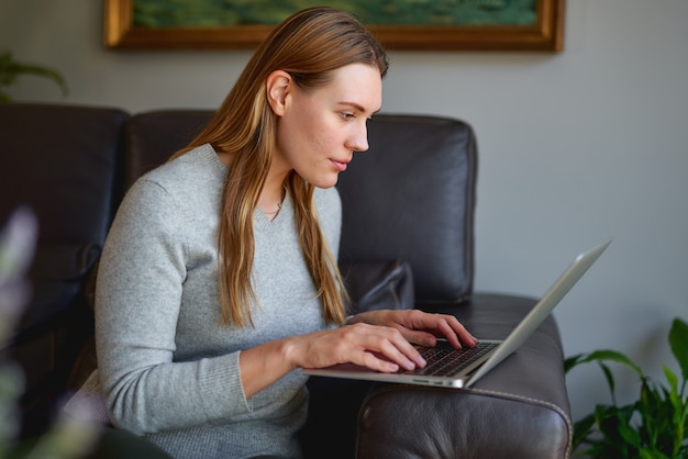 Bela jovem usando um laptop em casa