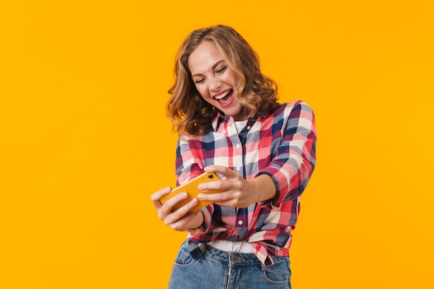 bela jovem vestindo camisa xadrez sorrindo e segurando o celular isolado