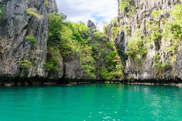 Bela lagoa com águas cristalinas azul-turquesa cercada por altos penhascos na ilha de Palawan, Filipinas