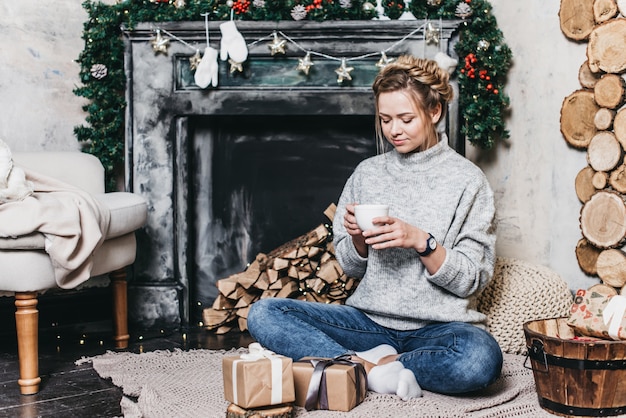 Bela linda em um suéter quente perto da lareira. conceito de natal e ano novo