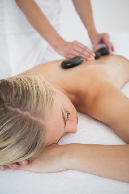 Bela loira desfrutando de uma massagem com pedras quentes
