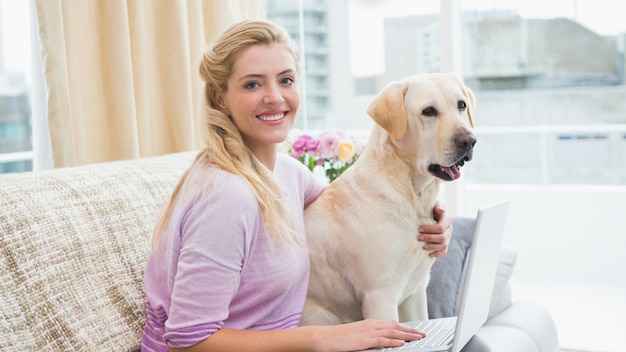 Bela loira relaxando no sofá com cachorro de estimação