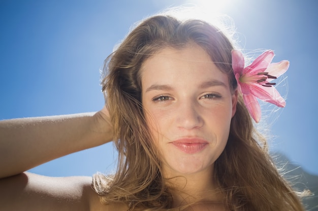 Bela loira sorridente com acessório de cabelo flor na praia