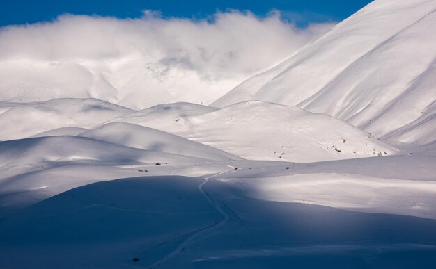 Bela luz do sol e sombras contrastam em colinas de neve no inverno
