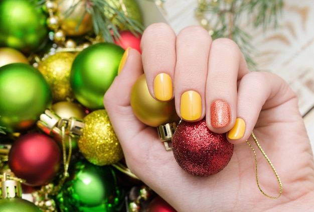 Bela mão feminina com design de unha amarela. manicure de natal.