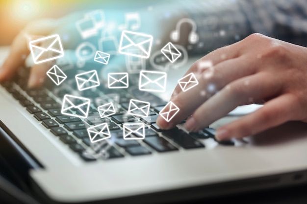 Bela mão trabalhando em um laptop com ícones de e-mail
