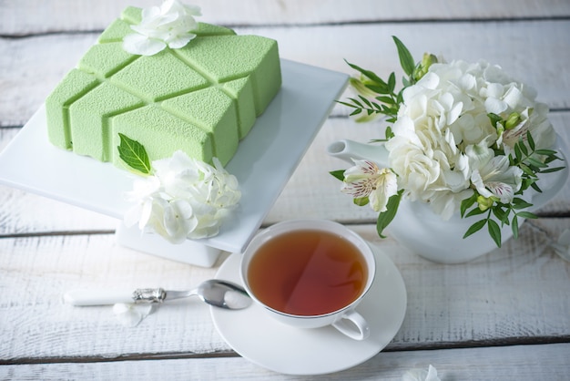 Bela mesa de chá de casamento de manhã com um bolo quadrado verde na prateleira e hortênsias brancas.