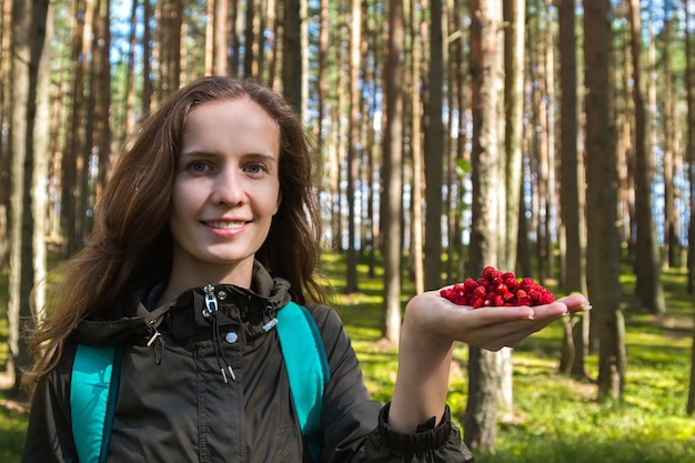 Foto bela moda mulher moderna pegando uma palma cheia de morangos na floresta.