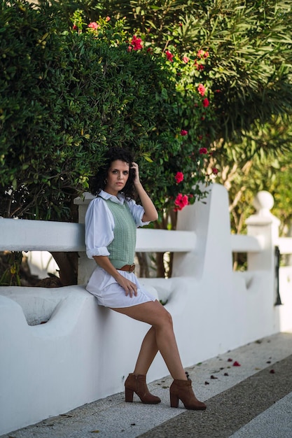 Bela modelo com cabelos cacheados e uma elegante roupa de outono posando perto de um parque