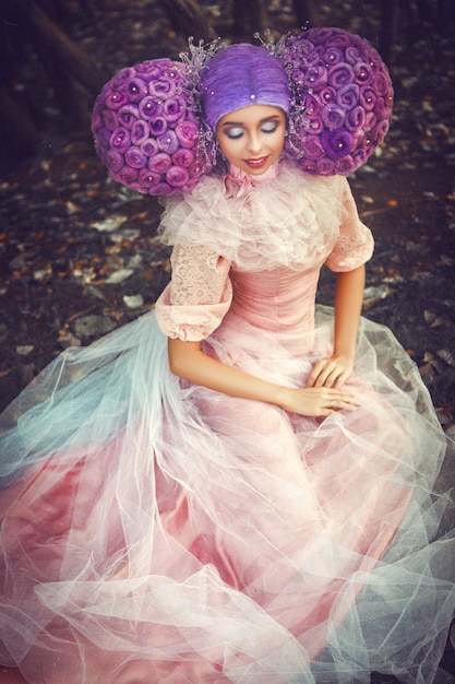 Bela modelo de vestido rosa está posando com uma peruca criativa