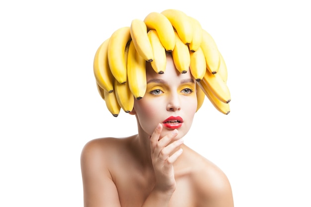 Bela modelo frágil com cacho de bananas na cabeça olhando para longe.