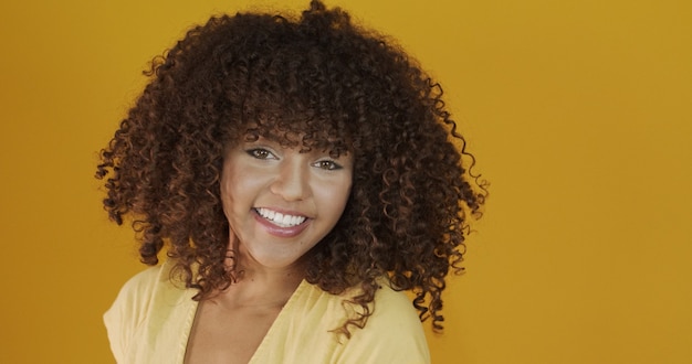 Bela modelo Moreno sorrindo para a câmera. Dentes lindos. Cabelo encaracolado. Jovem brasileira.