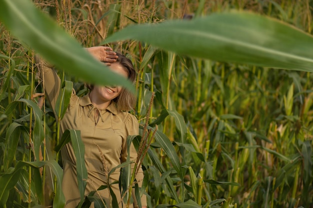 Bela modelo posando para a câmera no nascer do sol da manhã sobre o campo de milho Mulher divertida e alegre com um sorriso bonito