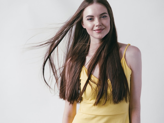 Bela morena com cabelo longo liso em retrato natural de camisa amarela sobre fundo branco