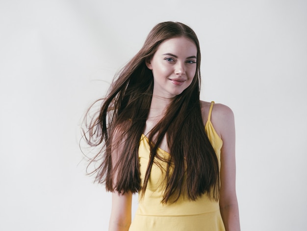 Foto bela morena com cabelo longo liso em retrato natural de camisa amarela sobre fundo branco