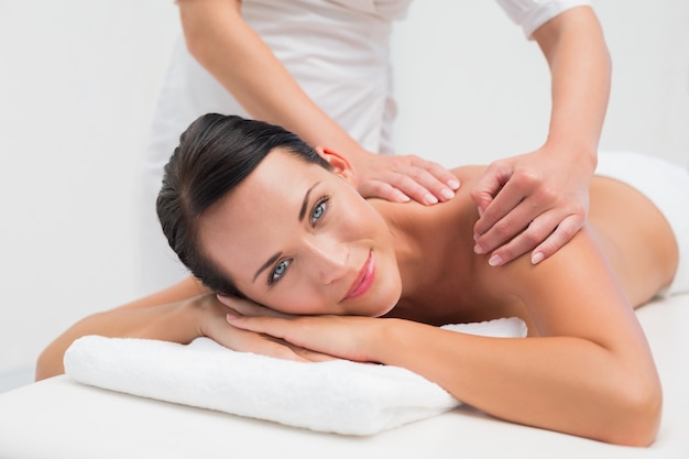 Bela morena desfrutando de uma massagem nas costas sorrindo para a câmera