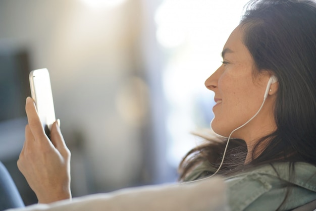 Bela morena falando no celular com fones de ouvido em casa