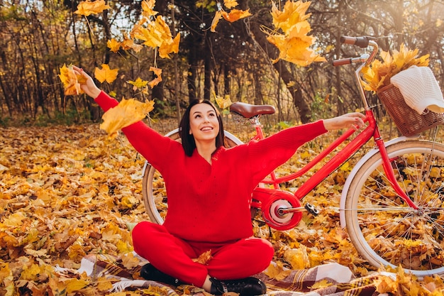 Bela morena na floresta de outono com uma bicicleta