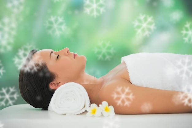 Bela morena relaxando na mesa de massagem contra flocos de neve