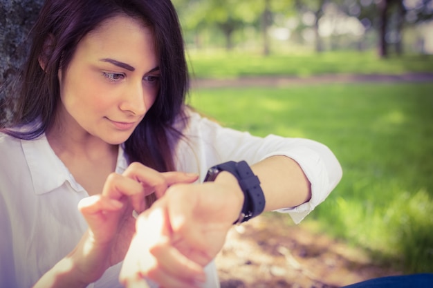 Bela morena usando smartwatch no parque